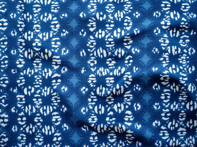 Indigo shibori fabric with intricate geometric patterns created through tie-dye techniques.